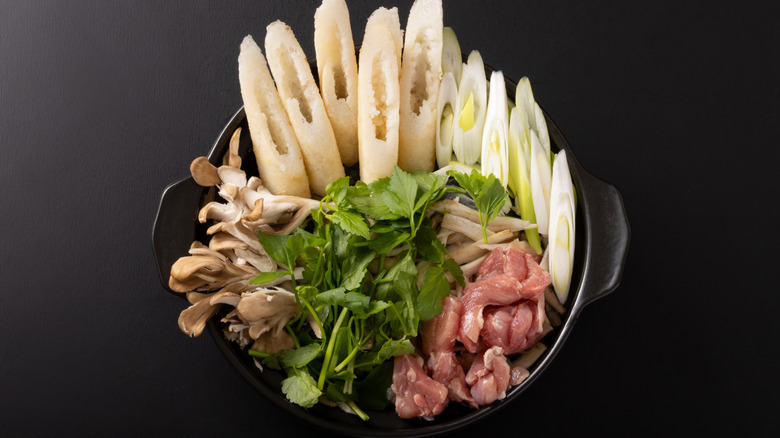 A bowl of mushrooms, meat, greens, and tofu in the Akita dish Kiritanpo Nabe