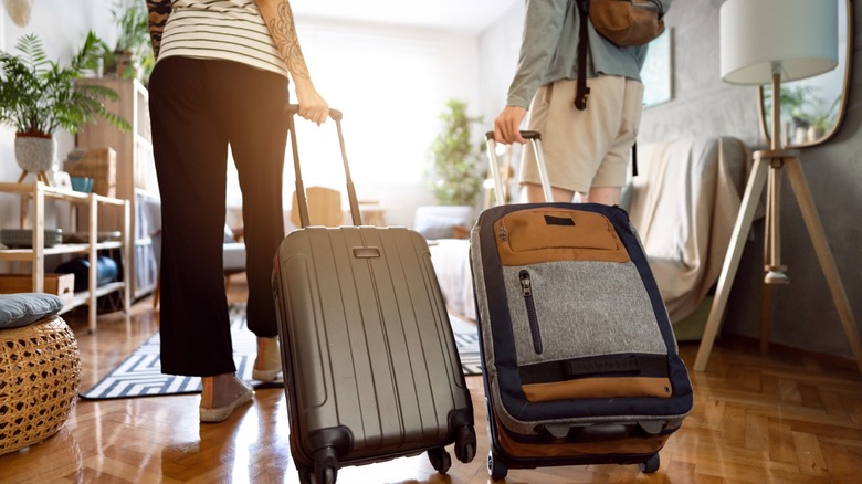 Two travellers arrive at their accommodation with suitcases in hand