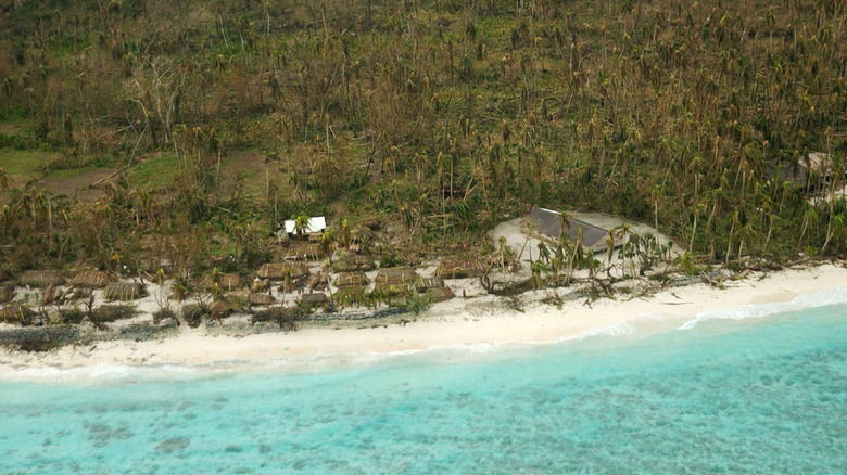 Verdant vegetation and village on crystal clear Solomon Island shores