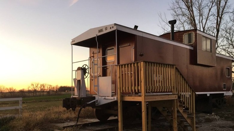Restored train caboose in field at sunset