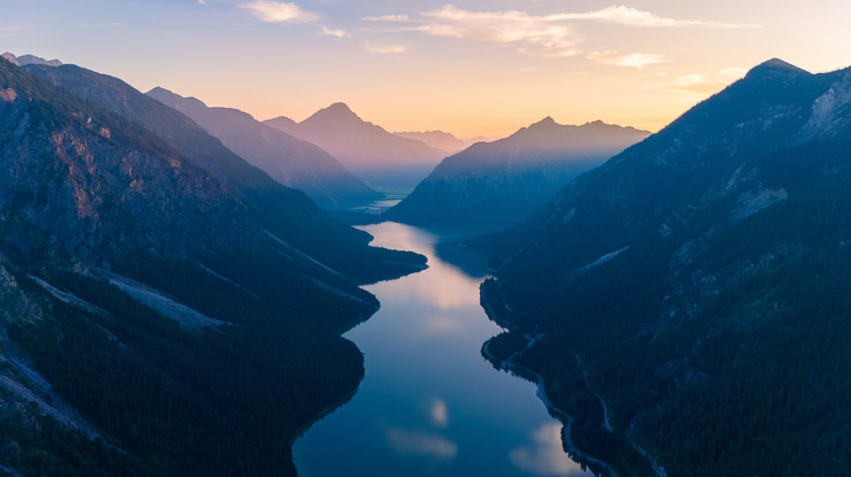 Lake Plansee reflects the sunrise, framed by mountains on both sides