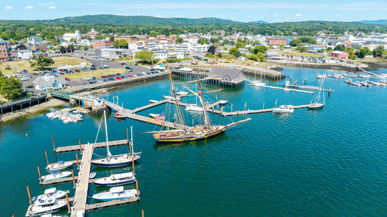 Aerial view of the turquoise waters and tree-lined streets of Rockland, Maine, in Knox County, with rolling hills in the background