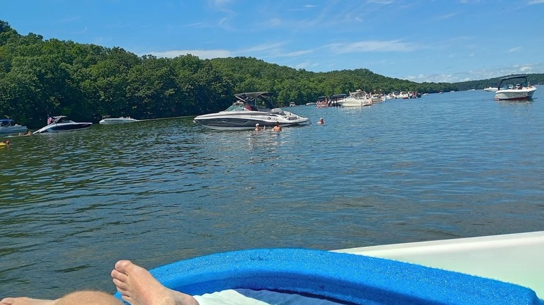 Multiple boats drifting on the calm waters at Lake of the Ozarks State Park, surrounded by lush rolling hills.