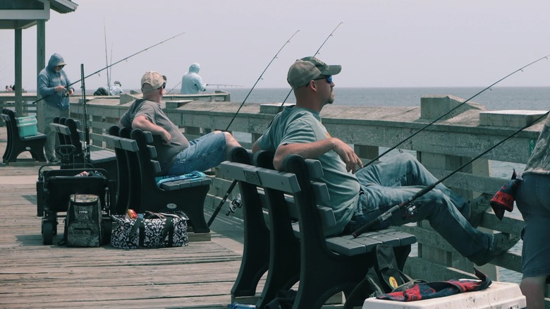 Fishermen sit with their poles on Jennette's Pier and look out toward the ocean