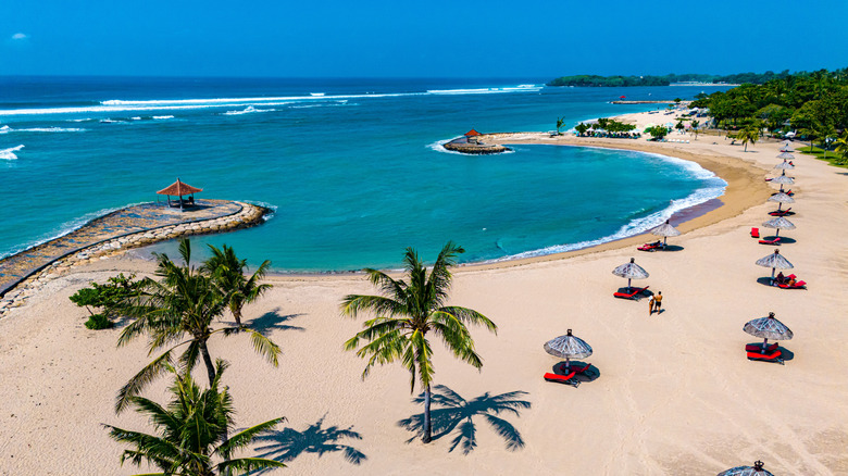 Daybeds on the golden sand beach of Nusa Dua in Bali.