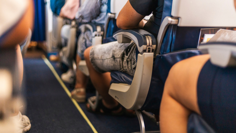 An airplane aisle with people sitting in the aisle seats
