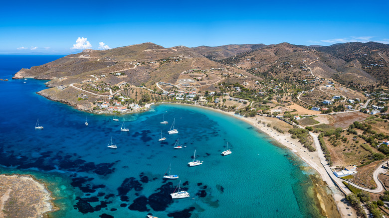 Boats in blue water near a sandy beach on Kea in Greece