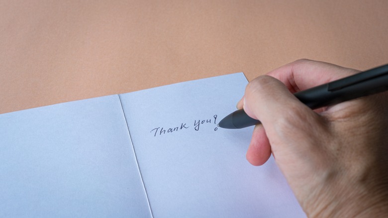 Someone writing in a "thank you" card