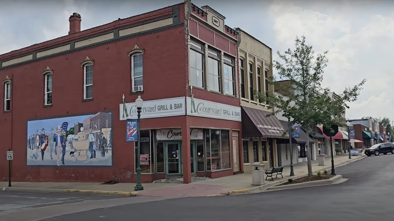 A red building in Clinton, MO, with a mural, standing on a street with lamppost
