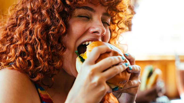 Woman biting into hamburger