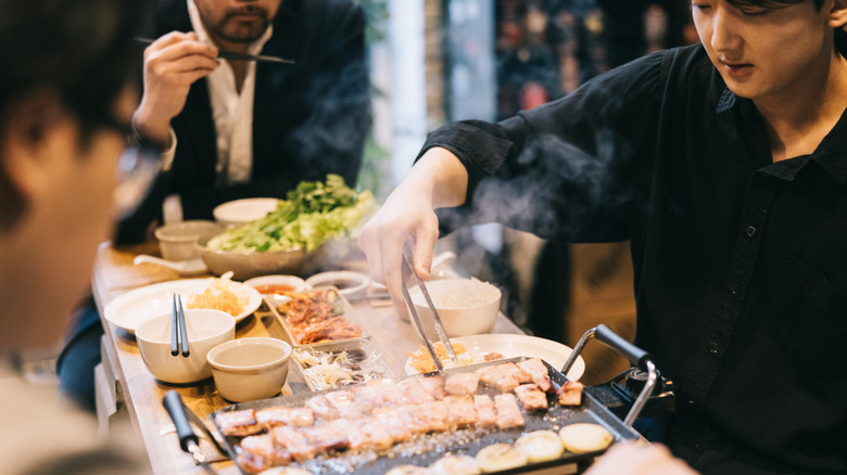 Diners sizzle meat in an Asian barbecue