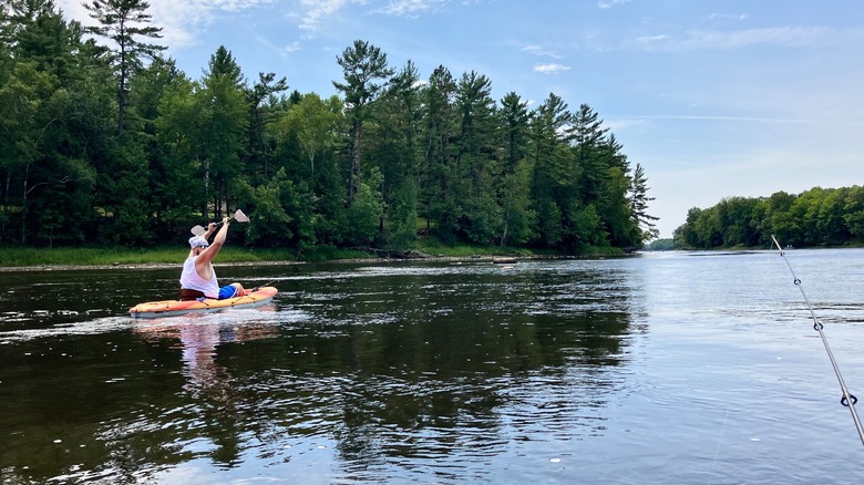 A person paddleboarding on the Menominee River and another fishing at the Menominee River State Recreation Area, Wisconsin-Michigan border