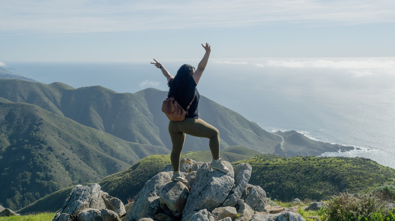 A hiker stands on a rock overlooking the Big Sur coastline