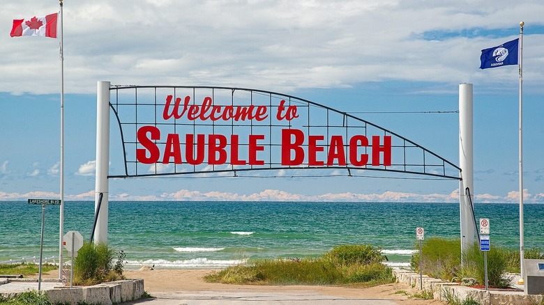 Red Welcome to Sauble Beach sign at beachfront entrance