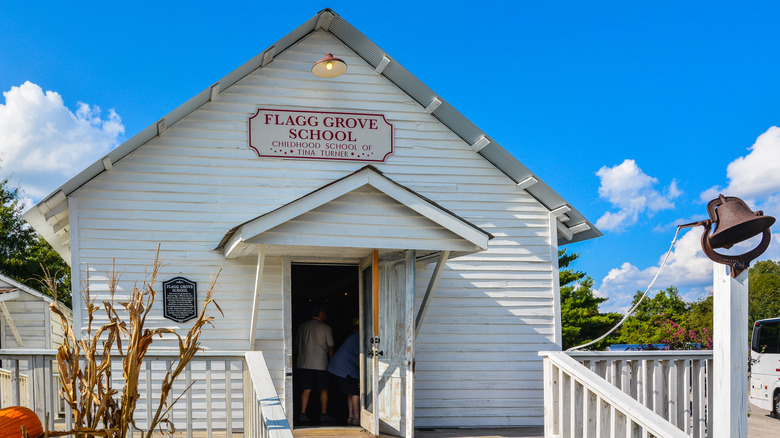 white building with sign reading Flagg Grove School, blue sky