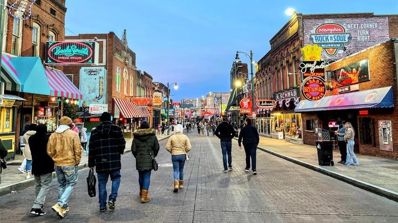 brick buildings with neon signs and awnings, pedestrians