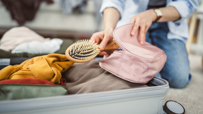 Woman packing suitcase with cosmetics