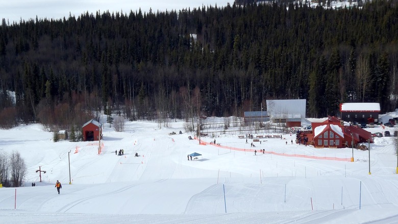 Snowy hills with sparse buildings and trees in background