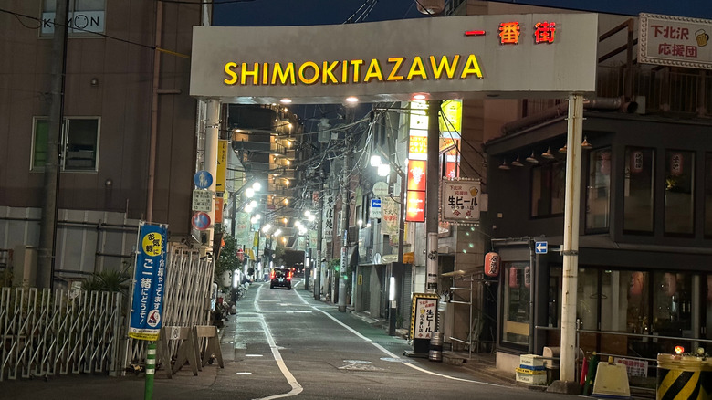Lit up Shimokitazawa sign above a street at night
