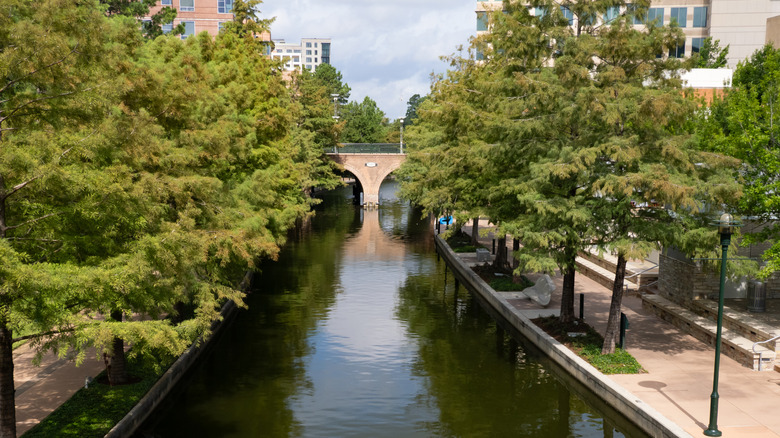An aerial view of the Waterway lined with trees on a cloudy day in The Woodlands, TX