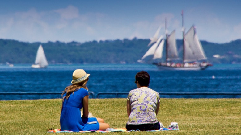 Two women face West Arm Grand Traverse Bay and watch sailboats go by
