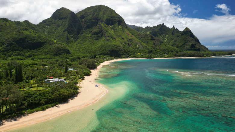 The ariel view of Tunnels Beach shoreline, ocean, and lush mountains.