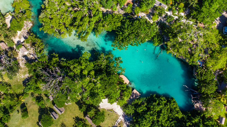 Drone shot of a lagoon with turquoise waters surrounded by cliffs and trees
