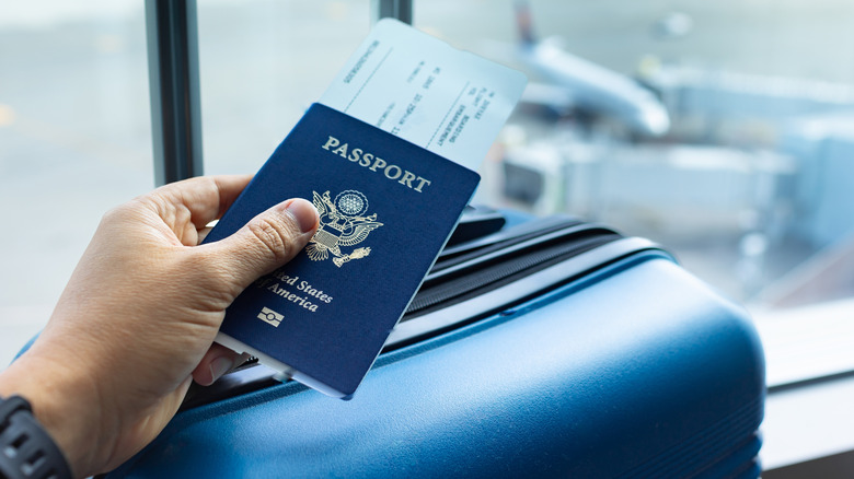 Close-up of a man holding his passport and his luggage at an airport