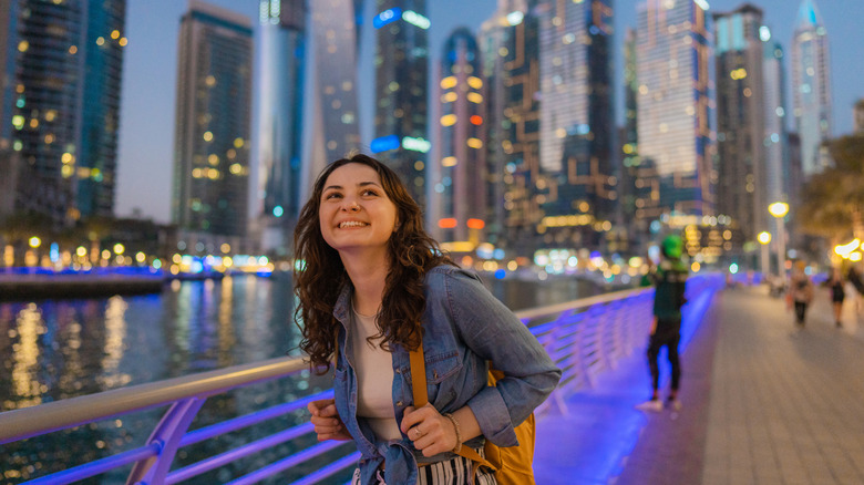 A young solo woman walking along Dubai Marina at night