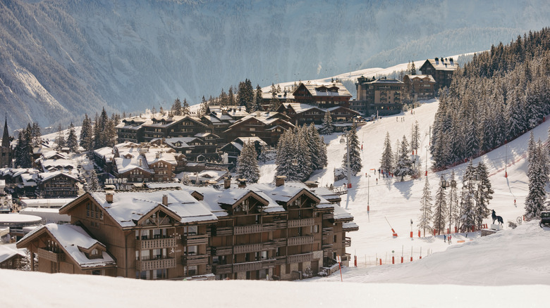 Night-time view of Fouquet's Courchevel, surrounded by evergreens and decorated with twinkling yellow lights.