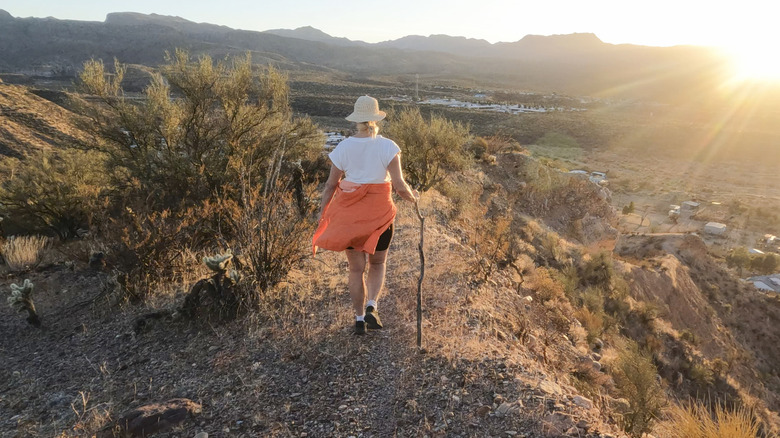 A woman hiking a small desert hill in Northern Arizona as the sun sets