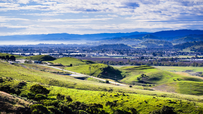 View of Morgan Hill, California in the distance with hills and mountains in the background during the day.