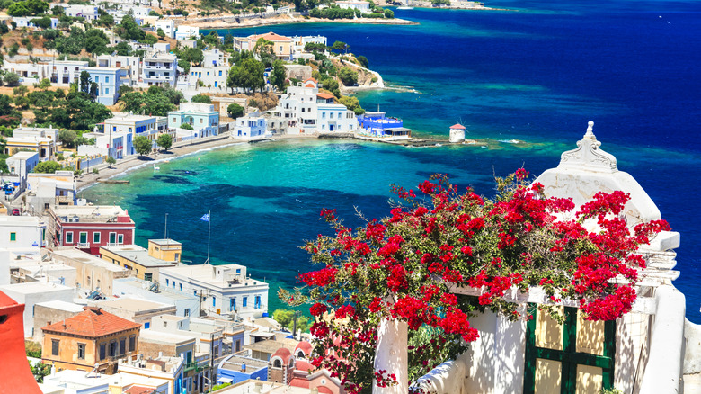 Terrace with red flowers overlooking town on blue water by with