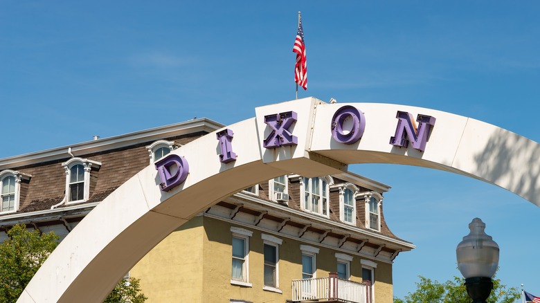 The Dixon Arch on a clear day in downtown Dixon, Illinois, with pretty yellow historic building in the background
