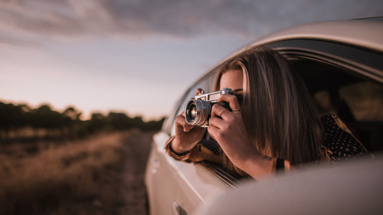 Woman taking a photo of the landscape from her car
