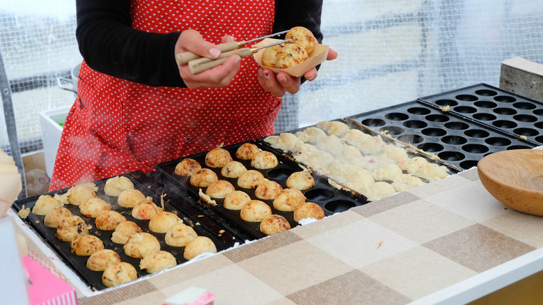 Person making and holding Takoyaki at the Takayama morning market in Japan