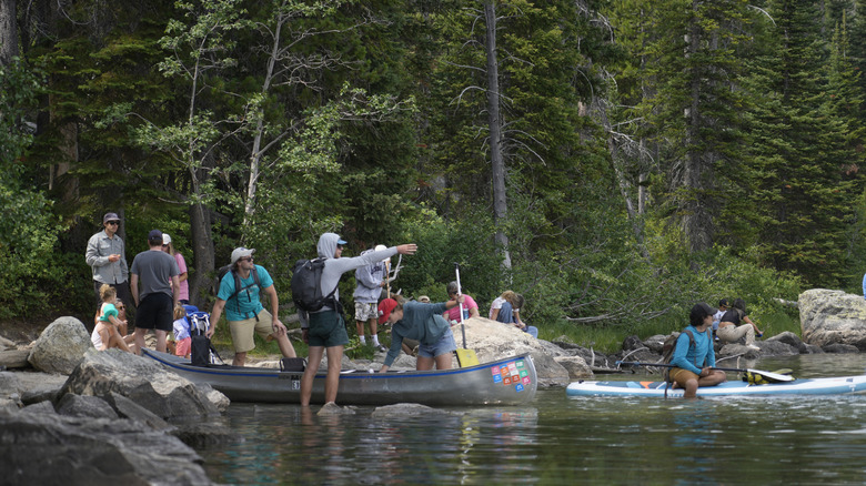 Group of campers getting into kayaks and on paddleboards at Leigh Lake in Grand Teton National Park