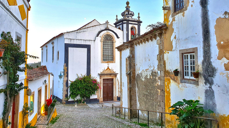 A colorful street in Óbidos, Portugal with white church