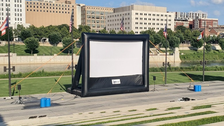An inflatable screen held up by ropes placed outdoors with Columbus city buildings in the background.