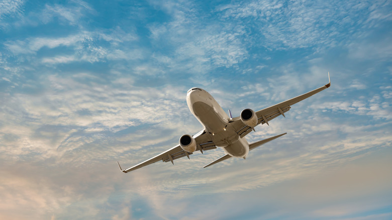 Airplane flying overhead against cloudy sky.