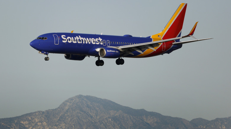 A Southwest Airlines Boeing 737 aircraft approaches Los Angeles International Airport in California, USA, for landing, with mountains visible in the background.