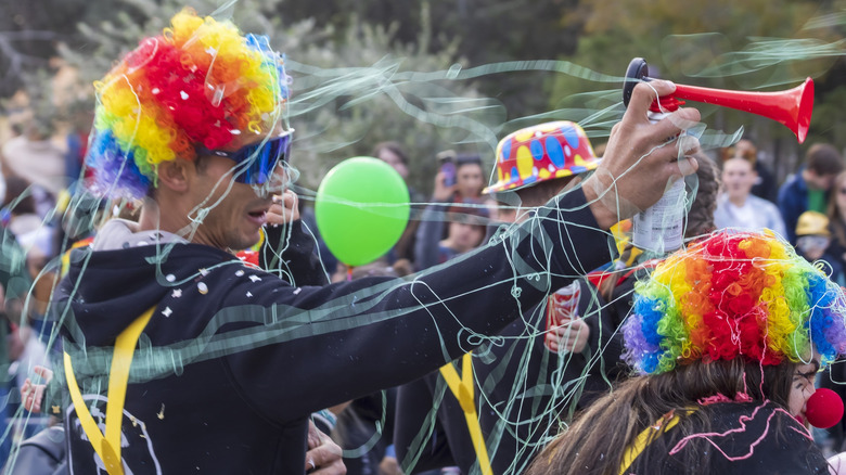 Person dressed as clown in parade sprayed with Silly String