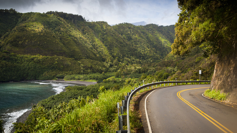 The scenic Hana Highway winding past cliffs on one side and the Pacific ocean, on the island of Maui, Hawaii