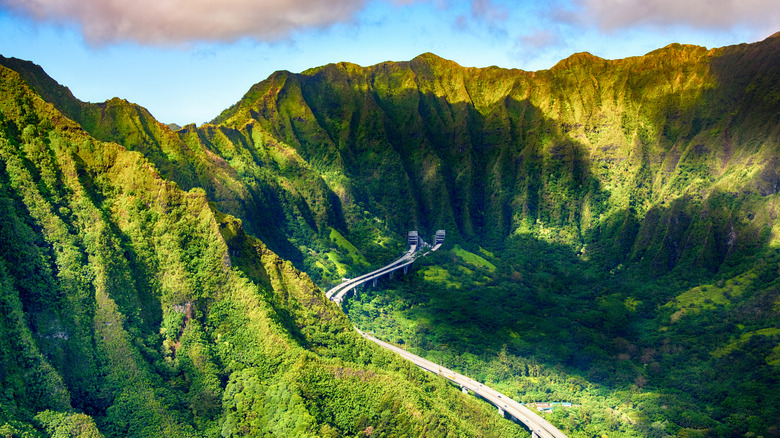The H-3 highway curving through lush tropical mountains and into distant tunnels on Oahu
