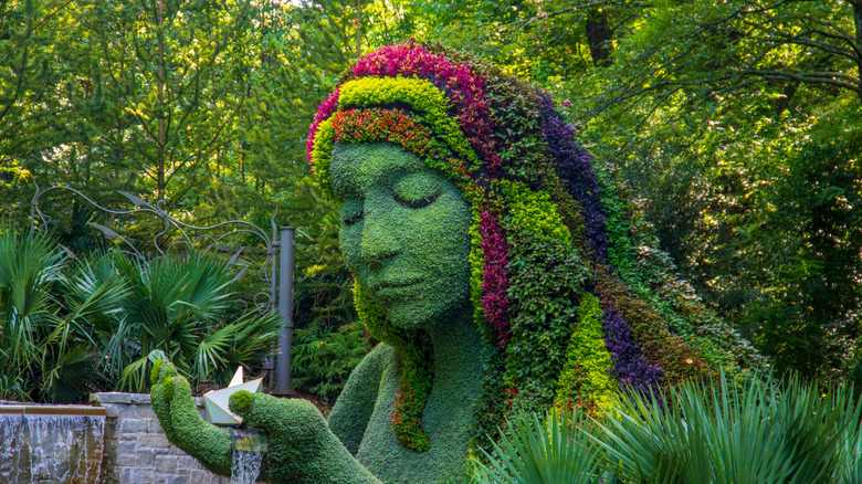 Lush plants and flowers growing on the "Earth Goddess" sculpture at the Atlanta Botanical Garden.