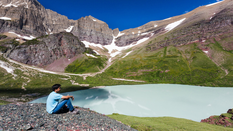Hiker enjoying the view at Cracker Lake in Glacier National Park, Montana