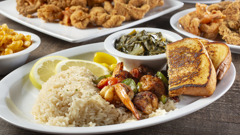 Plates of Southern foods like rice, shrimp, and collard greens on a plate