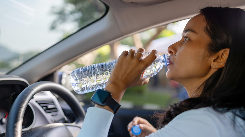 A person drinking water in the car