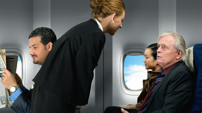 Flight attendant talking to a passenger on a plane