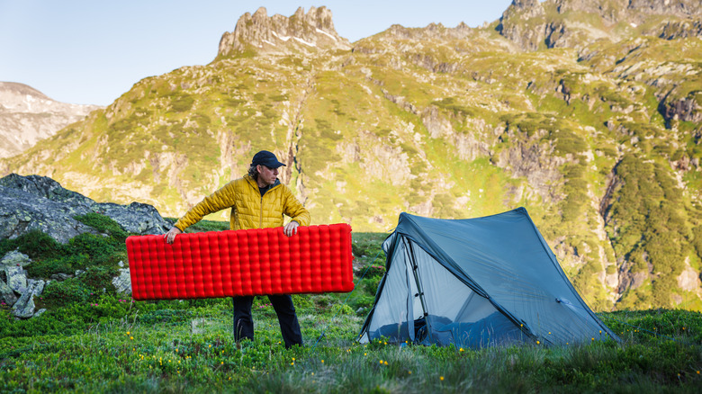 Man in the mountains putting sleep mat in a tent